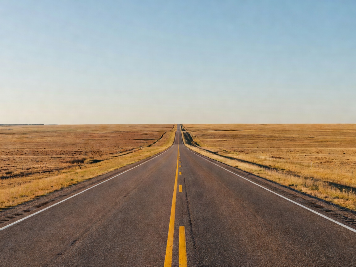 Endless straight highway stretching across a flat prairie landscape