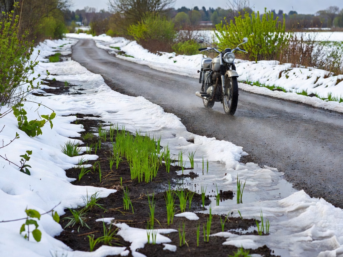Motorcycle riding past melting snow and early spring greenery